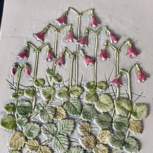 May include: A relief tile with a botanical design of pink bell-shaped flowers and green leaves. The flowers are on slender stems, and the leaves have detailed veining. The background is a textured, off-white colour.