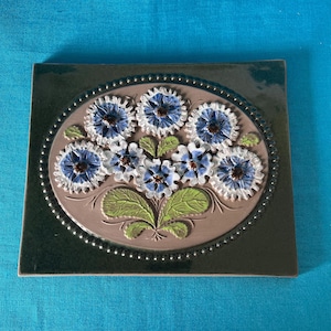 Flowery JIE vintage ceramic wall hangings from Sweden. 1 with pink flowers and 1 with blue. Dark green background. Made in the 1970's.