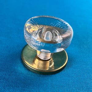 Könnte beinhalten: Ein klarer Glas-Türknopf mit strukturierter Oberfläche und Messingsockel.