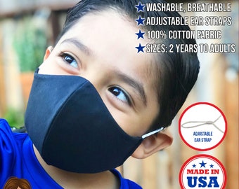 May include: Black fabric face mask with adjustable ear straps. The mask is made of 100% cotton and has three layers. The text "FABRIC MASK USA" is printed below the image. The text "MADE IN USA" is printed in a star-shaped design.