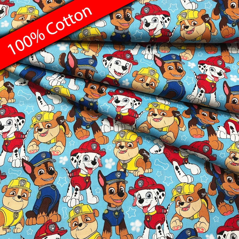 Pu&ograve; includere: Tessuto di cotone blu con un motivo ripetuto di cani dei cartoni animati dello show televisivo Paw Patrol. I cani indossano le loro uniformi distintive e hanno stelle e ossa sullo sfondo. Il tessuto dice "100% Cotone" in rosso.