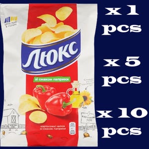 May include: A white bag of Lux potato chips with a red vertical stripe, featuring a graphic of golden chips, two red bell peppers, and a small bottle of oil. The text "Люкс" is printed in large blue letters, with additional Ukrainian text.