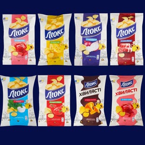 Puede incluir: Variedad de bolsas de patatas fritas con diferentes sabores, como queso, cebolla y cangrejo. Cada bolsa presenta la marca "Люкс" en azul y blanco, con ilustraciones coloridas de los ingredientes.