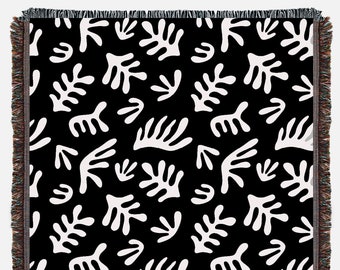 May include: Black and white woven throw blanket with a repeating pattern of abstract shapes resembling leaves and branches.