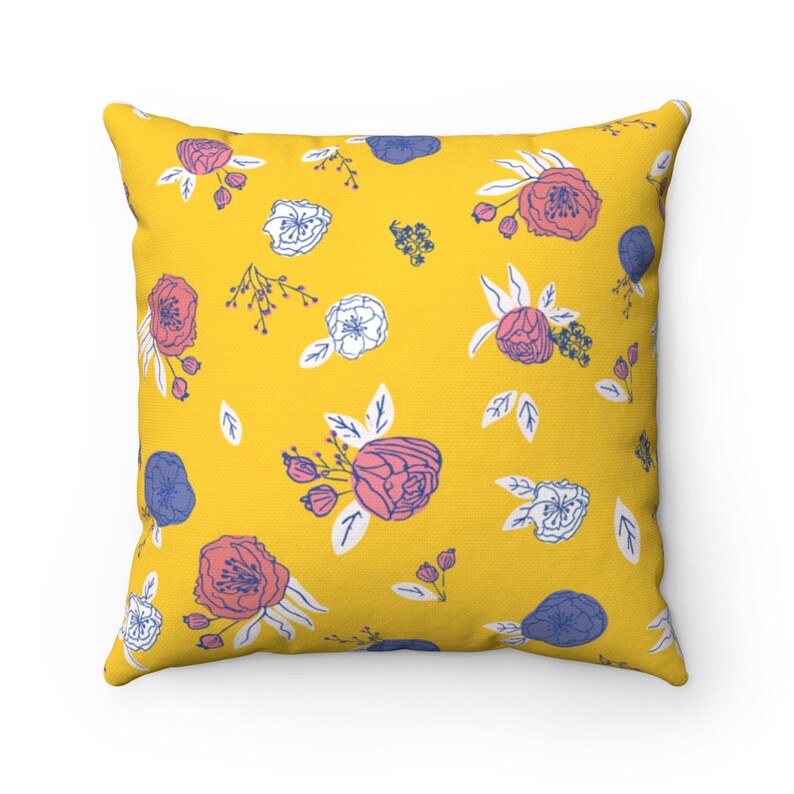 May include: A yellow throw pillow with a floral pattern featuring pink, white, and blue flowers.