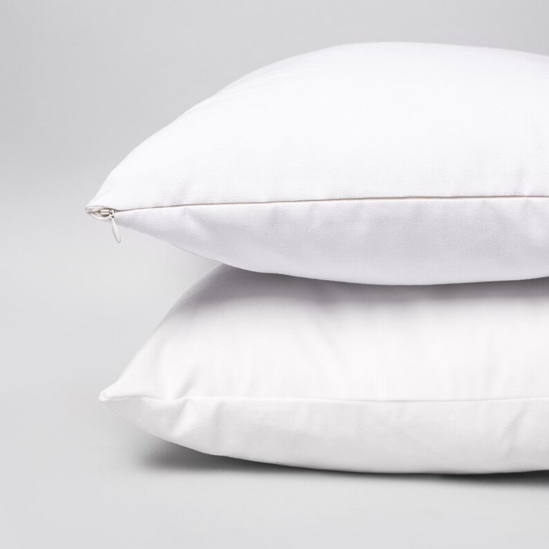 May include: Two white pillowcases with a zipper closure. The pillowcases are stacked on top of each other.
