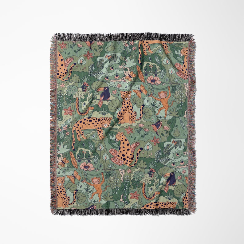 May include: A woven throw blanket with a green background and a repeating pattern of orange and black leopards, monkeys, toucans, and tropical plants.