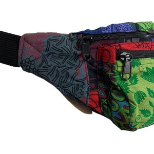 May include: A multi-coloured fanny pack with a black adjustable strap and multiple zippered compartments. The pack is made of a patchwork of different fabrics with floral and geometric patterns.