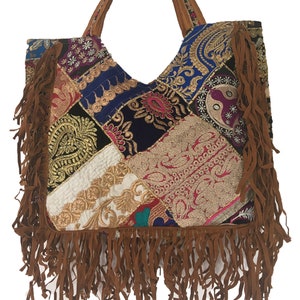 May include: A patchwork tote bag with a brown suede fringe. The bag is made of different fabrics with embroidered details in gold, pink, blue, and purple.