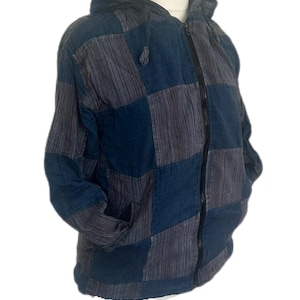 May include: A blue and grey patchwork hooded jacket. The jacket has a full-length zip and two front pockets. The fabric has a textured appearance. The design is made up of squares and rectangles.
