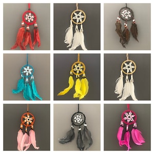 May include: Nine dreamcatchers with different coloured feathers and beads. The dreamcatchers are all circular and have a star-shaped design in the centre. The feathers are attached to the bottom of the dreamcatchers.