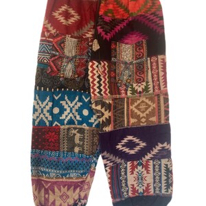 May include: Patchwork trousers with a colourful geometric pattern. The trousers have a drawstring waist and elastic cuffs. The fabric is a blend of cotton and wool.