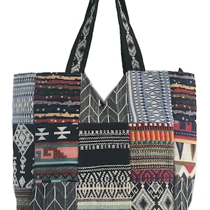 May include: A black tote bag with a patchwork design featuring colourful geometric patterns. The bag has two black straps.