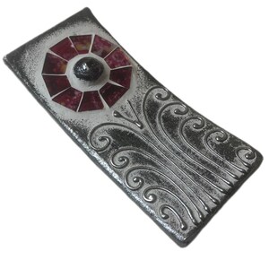 May include: A silver and white ceramic incense holder with a red and white mosaic design. The holder has a decorative swirl pattern.