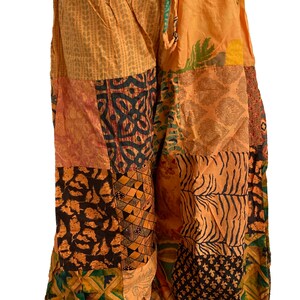 May include: Patchwork trousers with a drawstring waist. The trousers are made of different fabrics with various patterns in shades of brown, orange, green, and black.