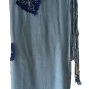 May include: A light blue wrap skirt with a blue and white embroidered flower design.