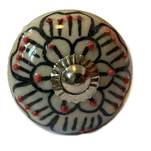 May include: White ceramic knob with a black and red floral design. The knob has a silver metal base.