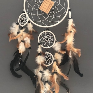 May include: White dream catcher with three hoops and brown and black feathers. The tag reads "Indian Dream Catcher".