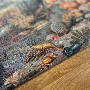 May include: A close-up of a completed jigsaw puzzle depicting a colorful underwater scene with a variety of sea creatures, including a crab, a lobster, and coral. The puzzle pieces are arranged in a way that creates a realistic and detailed image.