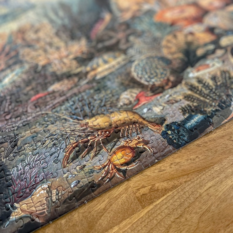 May include: A close-up of a completed jigsaw puzzle depicting a colorful underwater scene with a variety of sea creatures, including a crab, a lobster, and coral. The puzzle pieces are arranged in a way that creates a realistic and detailed image.