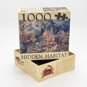 May include: A 1000 piece jigsaw puzzle box with a brown background and a colorful illustration of a hidden underwater habitat. The box has the text "HIDDEN HABITAT" on the front and the text "1000" on the top.