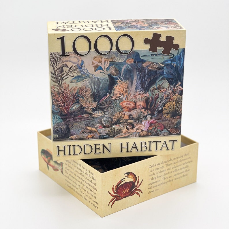 May include: A 1000 piece jigsaw puzzle box with a brown background and a colorful illustration of a hidden underwater habitat. The box has the text "HIDDEN HABITAT" on the front and the text "1000" on the top.
