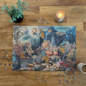 May include: A completed jigsaw puzzle depicting an underwater scene with colorful fish, coral, and sea life. The puzzle pieces are arranged on a wooden table with a lit candle and scattered puzzle pieces.