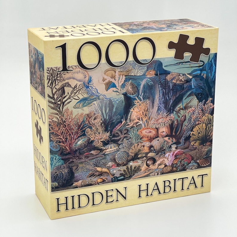 May include: A 1000 piece jigsaw puzzle with a colorful underwater scene. The puzzle box features a brown and white illustration of a variety of sea creatures, plants, and coral. The text "HIDDEN HABITAT" is printed on the box.