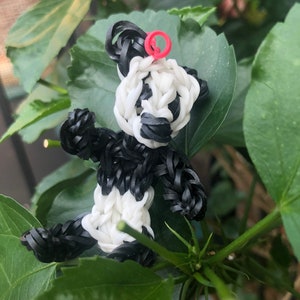 May include: A black and white panda bear made of rubber bands. The panda has a red rubber band on its head.