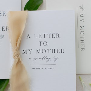 May include: A white card with the text "A Letter To My Mother on my wedding day October 8, 2022" and a beige ribbon tied around it.