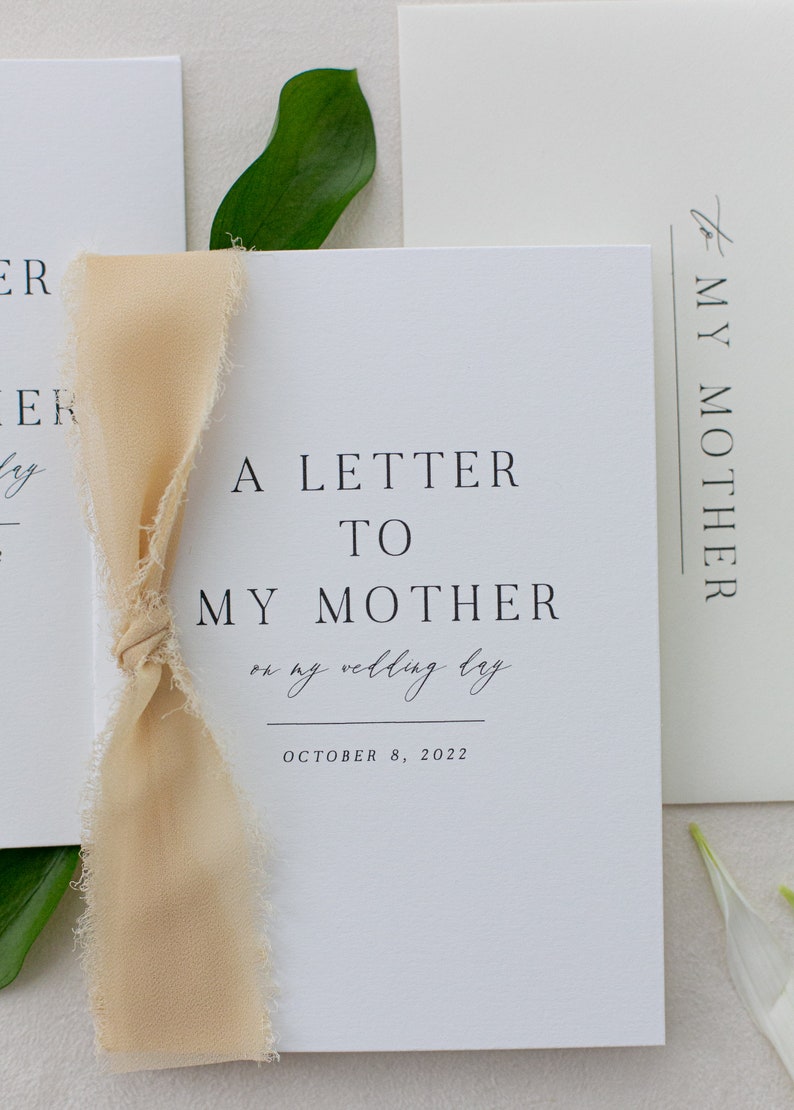 May include: A white card with the text "A Letter To My Mother on my wedding day October 8, 2022" and a beige ribbon tied around it.
