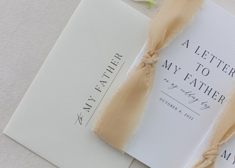 May include: A white card with the text "A Letter to My Father on my wedding day" and the date "October 8, 2022". The card is tied with a beige ribbon.