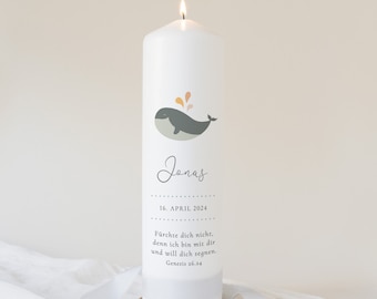 May include: A white pillar candle with a whale illustration and the name "Jonas" in script. The candle also includes the date "16. APRIL 2024" and a Bible verse. The candle is on a wooden coaster.