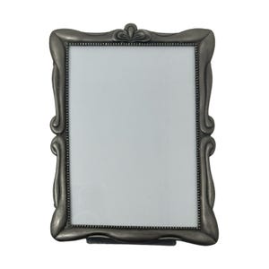 May include: A rectangular picture frame with a matte pewter-colored finish. The frame features a decorative border with curved, scroll-like edges and a small, fan-shaped ornament at the top center. The inner edge has a beaded texture detail.