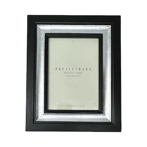 May include: A rectangular picture frame with a wide black outer border and a metallic silver inner border. The insert paper displays the text POTTERY BARN, heirloom frame, cadre de famille, and the dimensions 5 X 7 INCHES/12.7 X 17.8 CM.