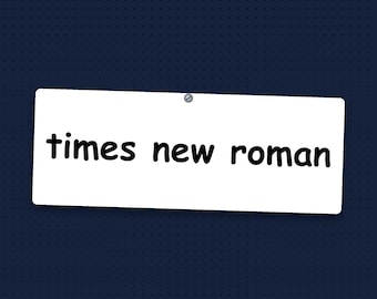 May include: A rectangular white sign with rounded corners, featuring the black lowercase text "times new roman" printed in a rounded sans-serif font. The sign is secured at the top center by a single small silver metal screw.