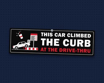 May include: A rectangular black sign with white and red text reading THIS CAR CLIMBED THE CURB AT THE DRIVE-THRU. The graphic features a white car driving over a red and white curb near a menu board with a spilled drink icon above it.