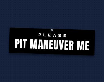 May include: A rectangular black sign with white text that reads PLEASE PIT MANEUVER ME. The sign features a small silver screw at the top center, securing it against a dark blue background with a subtle grid pattern of small dots.