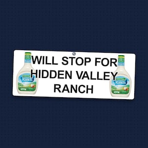 May include: A rectangular white sign with rounded corners and a single screw hole at the top center. The text WILL STOP FOR HIDDEN VALLEY RANCH is printed in black. Two bottles of Hidden Valley Ranch dressing are displayed on the sign.