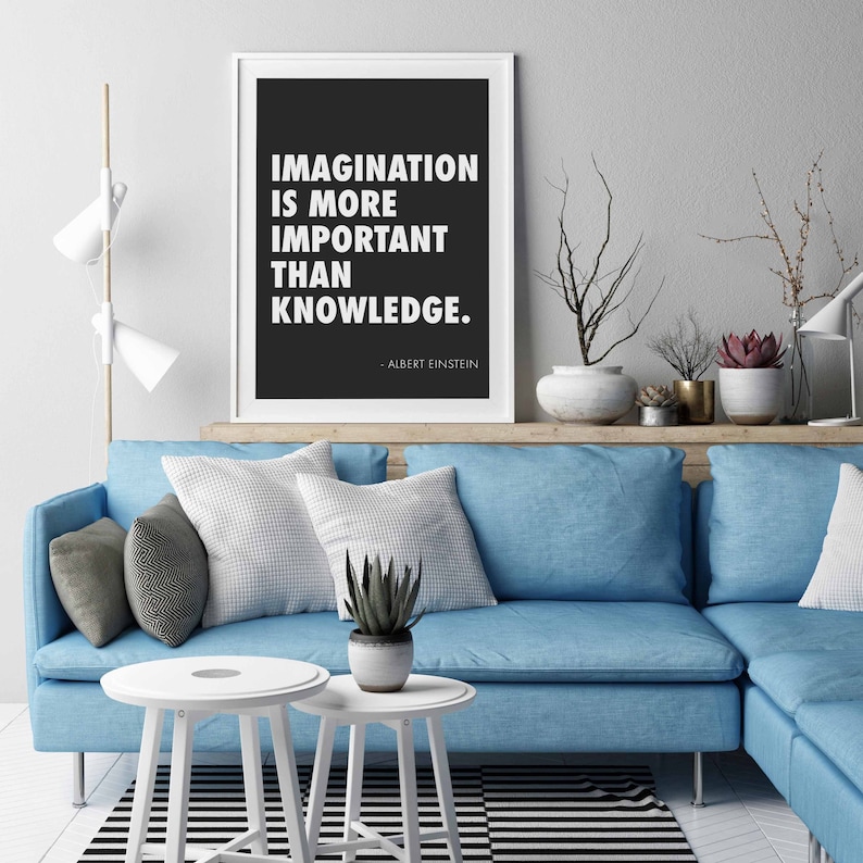Peut inclure: Une impression encadr&eacute;e en noir et blanc avec la citation "L'imagination est plus importante que le savoir." d'Albert Einstein. L'impression est accroch&eacute;e au mur au-dessus d'un canap&eacute; bleu avec des coussins et une plante.