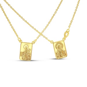 May include: Two gold necklaces with rectangular pendants featuring religious imagery. One pendant depicts the Virgin Mary holding a baby Jesus, while the other depicts Jesus with his heart exposed.