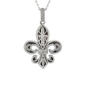 May include: Silver-toned fleur-de-lis pendant necklace. The pendant features a detailed design with clear, sparkling accents and a black background. The necklace has a delicate chain.