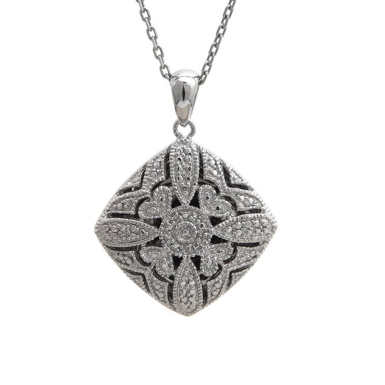 May include: A silver-toned necklace featuring a square pendant with an intricate, openwork design. The pendant is adorned with small, sparkling accents, and hangs from a delicate chain. The overall aesthetic is elegant and detailed.