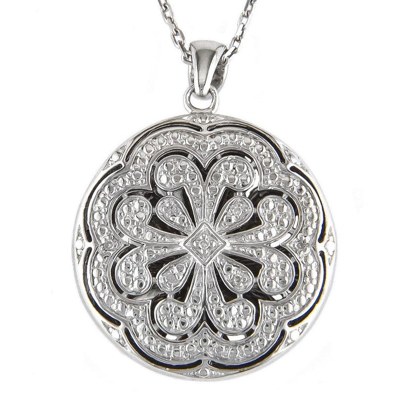May include: A silver-toned pendant necklace featuring a round, openwork design. The pendant has a floral pattern with small, sparkling accents. The necklace chain is also silver-toned, creating a cohesive and elegant look.