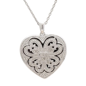 May include: Silver-toned heart pendant necklace. The pendant features an intricate openwork design with a heart-shaped outline and a delicate chain. The heart is embellished with small, sparkling accents, creating a detailed and elegant look.