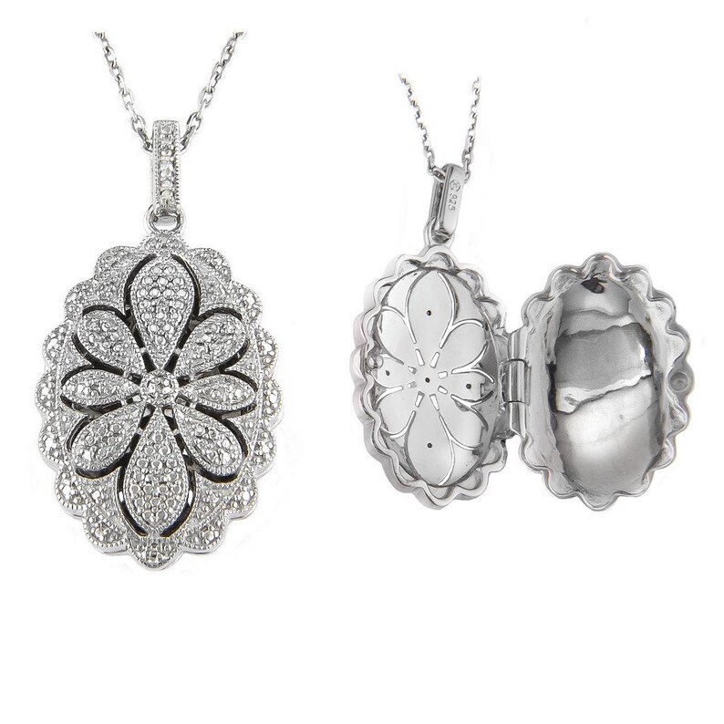 May include: A silver-toned locket necklace with a floral design. The pendant is oval-shaped and opens to reveal a compartment. The front of the pendant is encrusted with small, sparkling stones. The necklace chain is also silver.