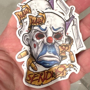 May include: A stack of stickers featuring a clown face with red eyes, a red nose, and blue accents. The stickers have the words "WHY" and "SO SERIOUS?" on them, along with bullet casings and a knife.