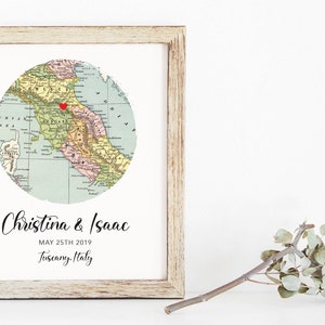 May include: A framed print with a vintage map of Tuscany, Italy, with a red heart marking a location. The text below the map reads "Christina & Isaac, May 25th 2019, Tuscany, Italy."