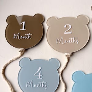May include: A set of three ceramic mugs with a speckled, matte finish. The mugs are in shades of cream, light gray, and dark gray. Each mug has a simple, minimalist design and a rounded handle.