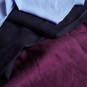 May include: An assortment of fabric swatches in shades of blue, navy, and burgundy. The fabrics are layered and crumpled, showcasing their textures and colors. Ideal for textile projects or design inspiration.
